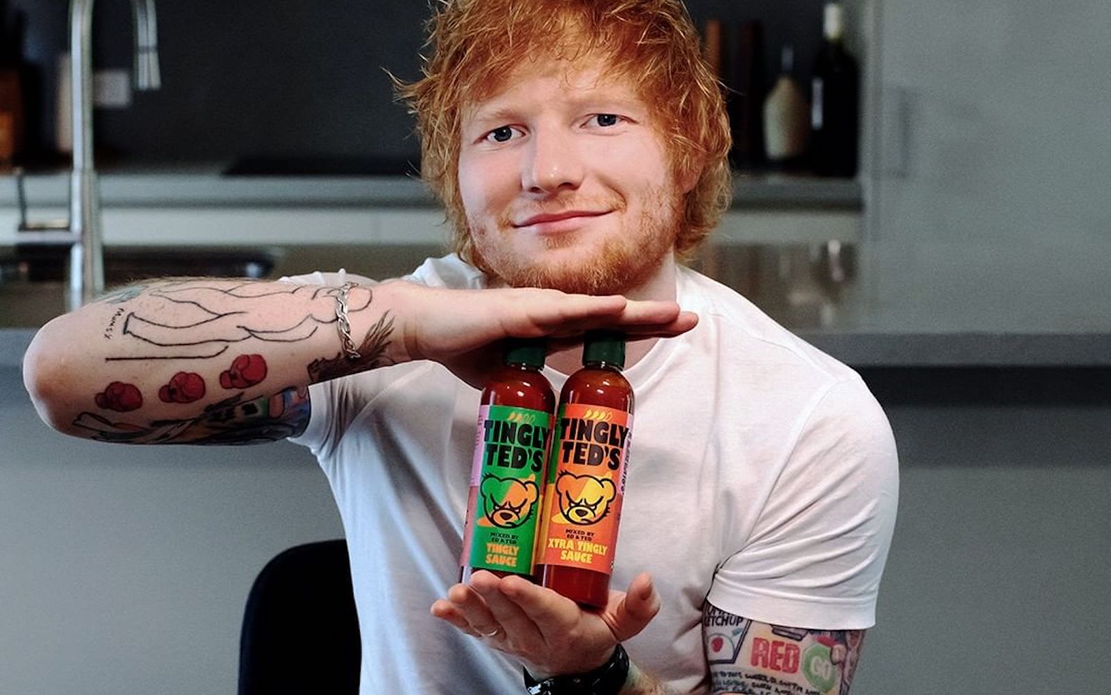 Ed Sheeran holding Tingly Ted's hot sauces.