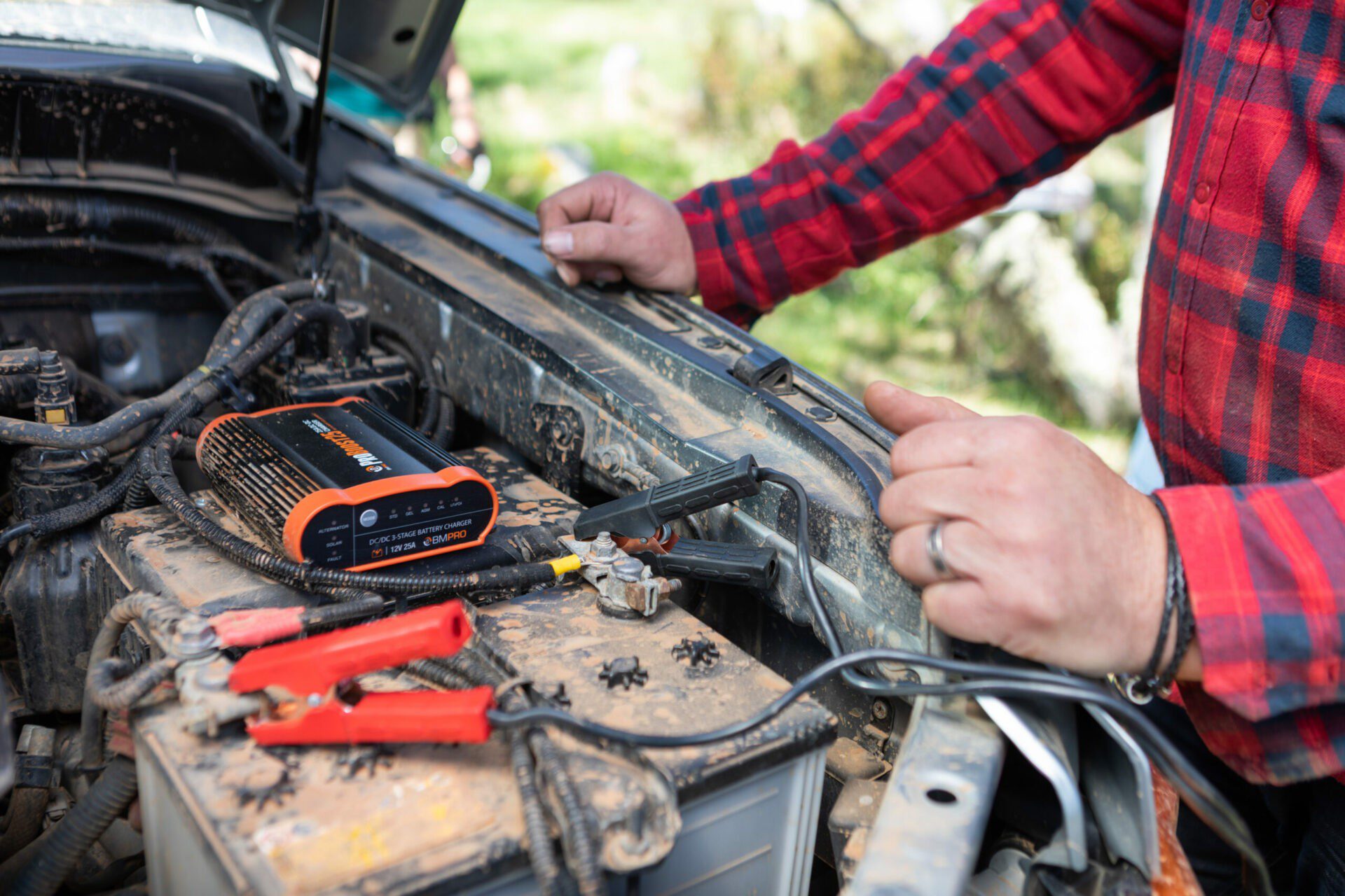 Man charging a car battery using a DC-DC battery charger.